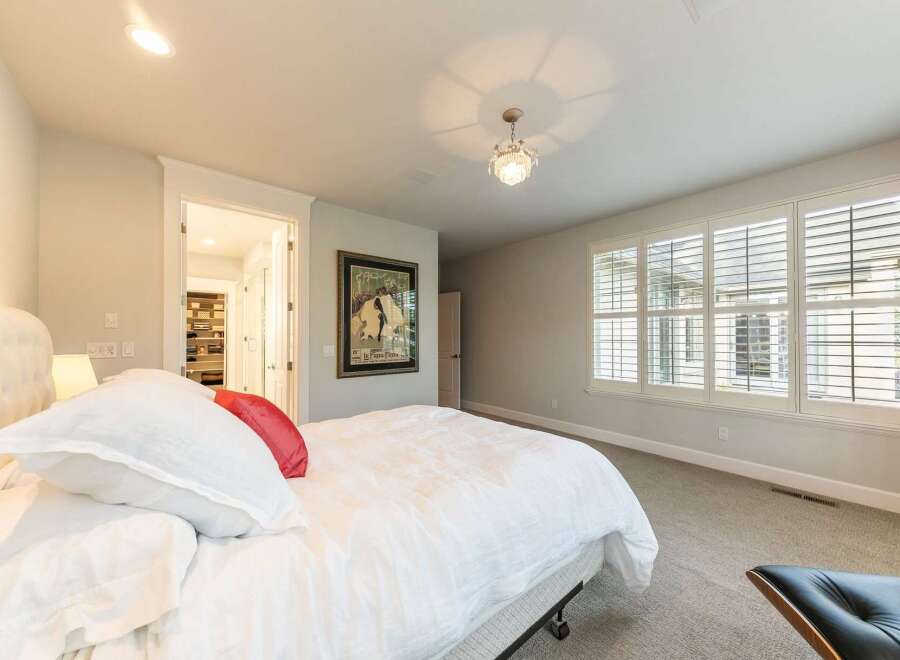 Experience luxury in this master bedroom, featuring a plush king-sized bed with crisp white linens and a vibrant red accent pillow.