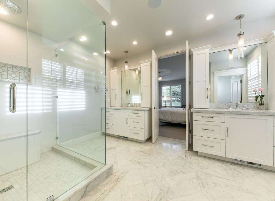Experience luxury in this stunning master bathroom featuring a spacious glass-enclosed shower with a rainfall showerhead and a built-in bench.