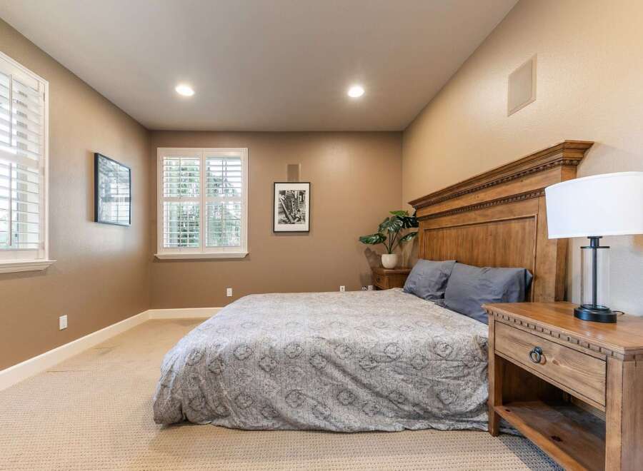 This inviting bedroom features a spacious king-size bed with a grand wooden headboard, complemented by plush grey pillows and a patterned comforter.