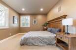 This inviting bedroom features a spacious king-size bed with a grand wooden headboard, complemented by plush grey pillows and a patterned comforter.