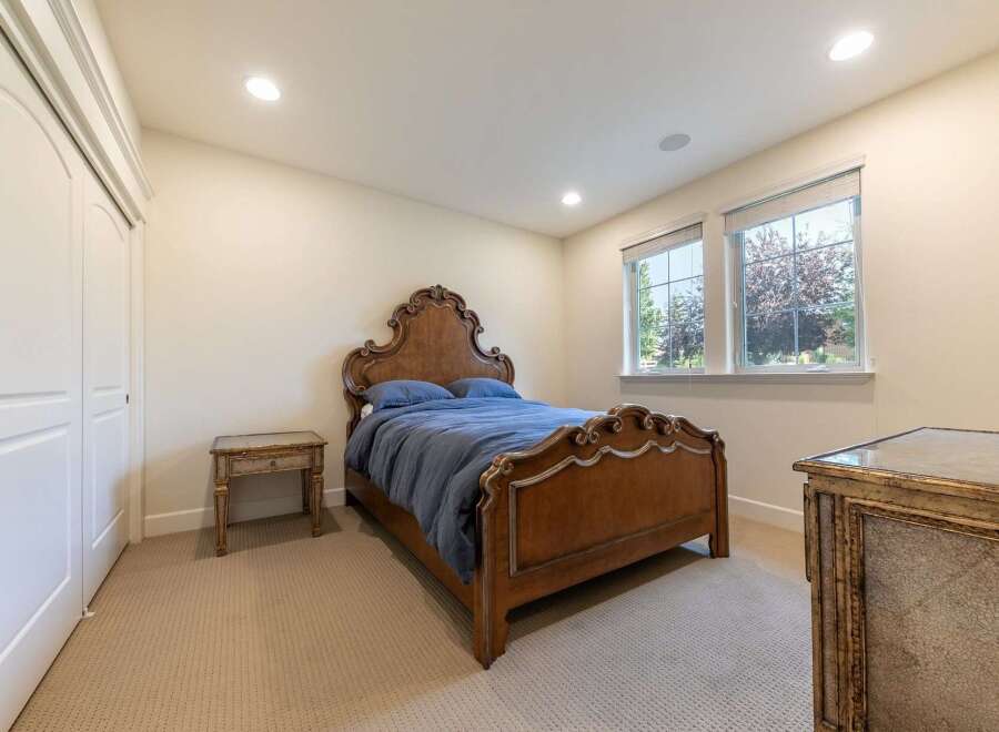 This charming bedroom features a beautifully ornate wooden bed with a plush blue comforter, complemented by a vintage-style nightstand.