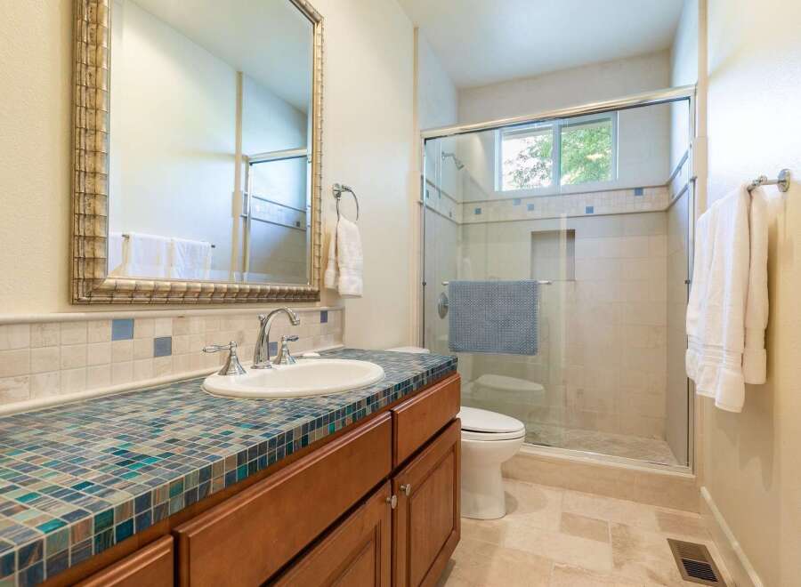 This beautifully appointed bathroom features a stunning mosaic tile countertop that adds a pop of color and texture.