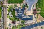 Discover this stunning aerial view of a luxurious estate, showcasing its expansive dark-shingled roofline and meticulously landscaped grounds.