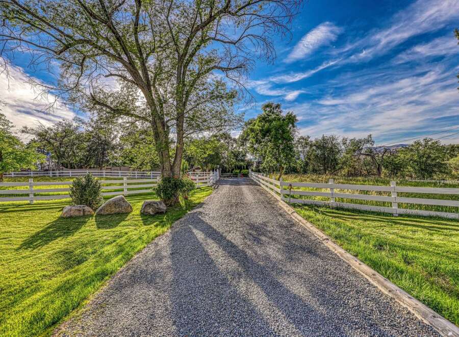 Discover this charming property featuring a picturesque tree-lined gravel driveway leading to a serene estate.