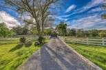 Discover this charming property featuring a picturesque tree-lined gravel driveway leading to a serene estate.