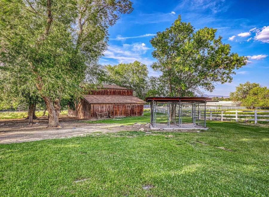 Discover this charming rural property featuring a rustic wooden barn and a spacious outdoor dog kennel, perfect for animal lovers.