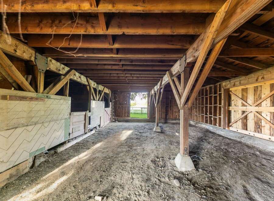 Explore the rustic charm of this spacious barn, featuring sturdy wooden beams and a durable dirt floor, perfect for agricultural use or conversion into a unique living space.