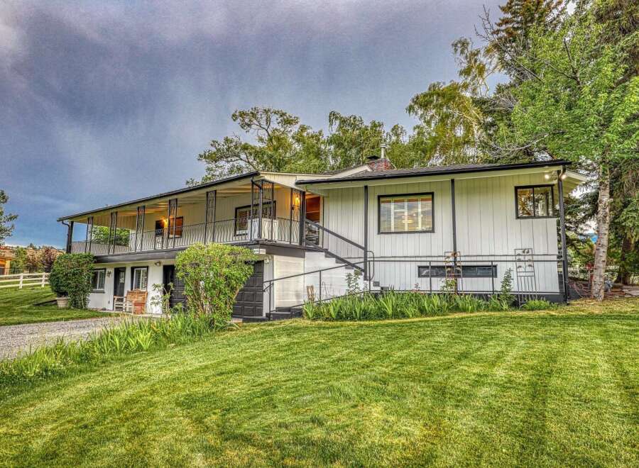Discover this charming white home featuring a wraparound porch perfect for enjoying the outdoors.