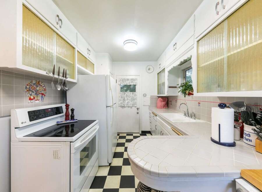 Step into this charming kitchen featuring a classic black and white checkered floor and ample white cabinetry.