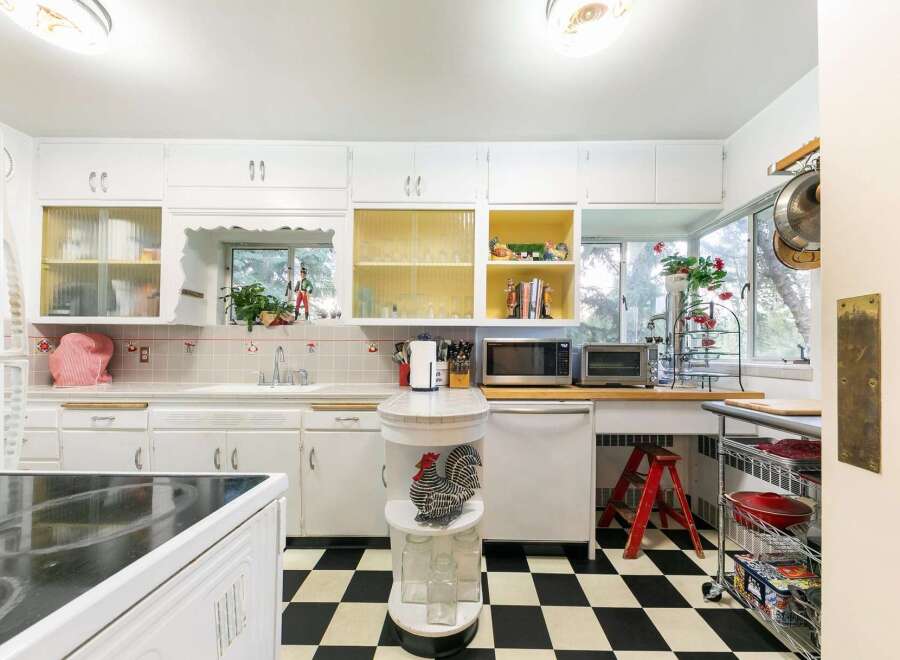 Step into this charming kitchen featuring a classic black and white checkered floor and ample white cabinetry.