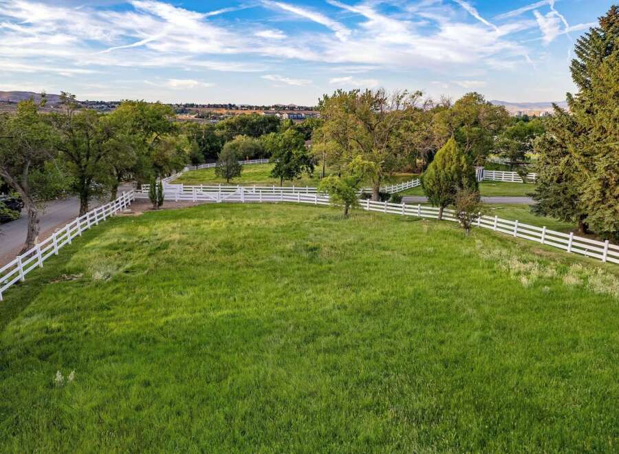 Experience the charm of rural living with this expansive property, featuring a picturesque white vinyl fence that encloses lush green pastures.