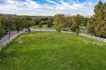 Experience the charm of rural living with this expansive property, featuring a picturesque white vinyl fence that encloses lush green pastures.