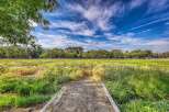 Discover serene living with this picturesque landscape, featuring lush green fields and a vibrant blue sky dotted with wispy clouds.