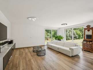 Experience modern living in this spacious living room featuring a plush white sectional sofa perfect for relaxation.