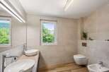 Experience modern luxury in this stunning bathroom featuring dual vessel sinks atop a sleek wooden vanity, complemented by a wall-mounted toilet and a matching bidet.