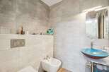 This modern bathroom features a sleek design with large format tiles on the walls and a unique blue vessel sink.