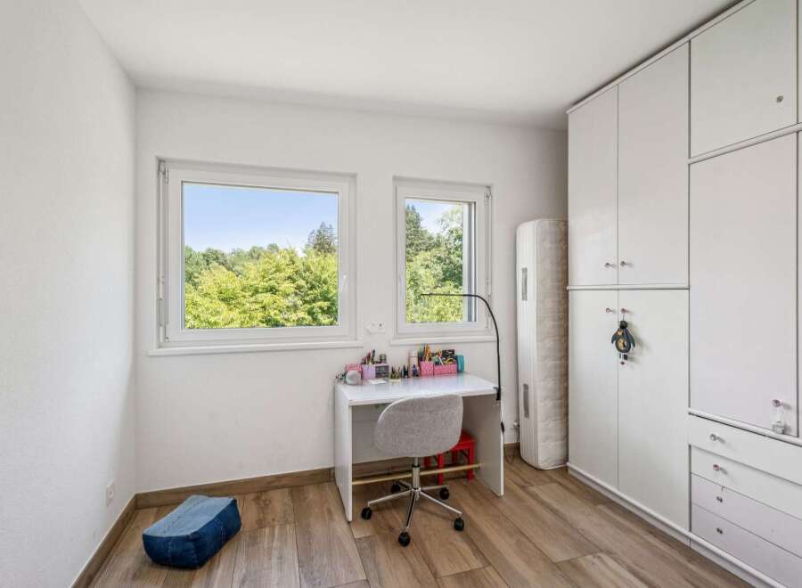 This bright and airy bedroom features a modern white desk with a swivel chair, perfect for studying or creative pursuits.