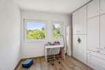 This bright and airy bedroom features a modern white desk with a swivel chair, perfect for studying or creative pursuits.