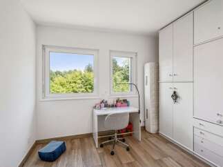 This bright and airy bedroom features a modern white desk with a swivel chair, perfect for studying or creative pursuits.