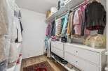 Discover ample storage in this well-organized walk-in closet, featuring a comprehensive shelving system and multiple drawers.