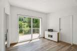 Step into this bright and airy room, featuring a large sliding glass door that opens to a balcony with a scenic view of lush greenery.