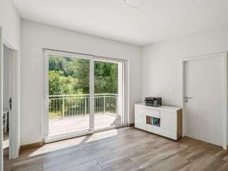 Step into this bright and airy room, featuring a large sliding glass door that opens to a balcony with a scenic view of lush greenery.