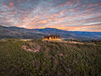 Experience breathtaking sunset views from this stunning mountain home, perched atop a lush hillside.