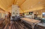 Experience ultimate relaxation and entertainment in this stunning log cabin living space, featuring a grand stone fireplace and a spacious seating area perfect for gatherings.