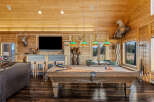 Experience rustic luxury in this spacious game room, featuring a professional billiard table perfect for evening entertainment.