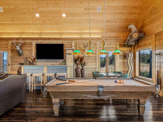 Experience rustic luxury in this spacious game room, featuring a professional billiard table perfect for evening entertainment.