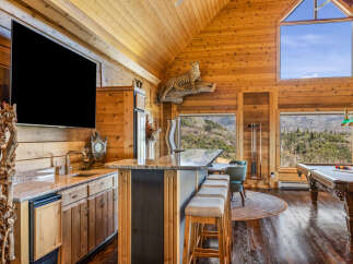 Experience ultimate relaxation in this stunning log cabin retreat, featuring a fully equipped bar area with granite countertops and a mini-fridge, perfect for entertaining.