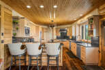 Experience rustic elegance in this stunning kitchen, featuring warm wood paneling on the ceiling and walls, complemented by light wood cabinetry.