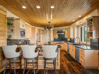 Experience rustic elegance in this stunning kitchen, featuring warm wood paneling on the ceiling and walls, complemented by light wood cabinetry.