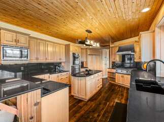 Experience luxury in this stunning kitchen featuring custom light wood cabinetry and sleek black granite countertops.