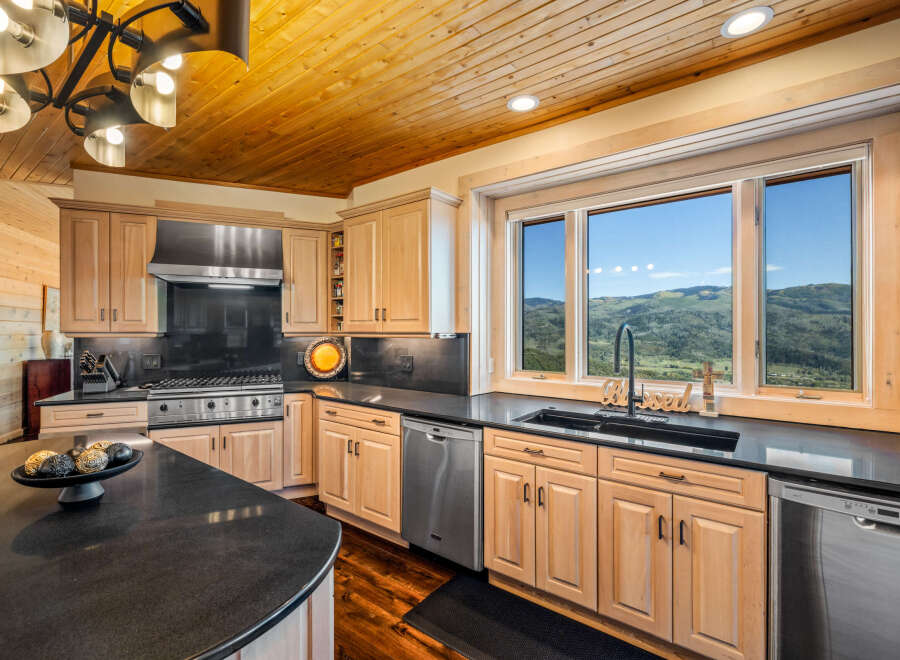 Experience breathtaking mountain views from this stunning kitchen, featuring a spacious island with granite countertops and a full suite of stainless steel appliances.