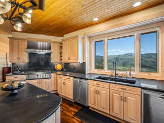 Experience breathtaking mountain views from this stunning kitchen, featuring a spacious island with granite countertops and a full suite of stainless steel appliances.