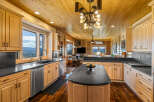 Experience breathtaking mountain views from this stunning kitchen, featuring elegant light wood cabinetry and sleek black countertops.