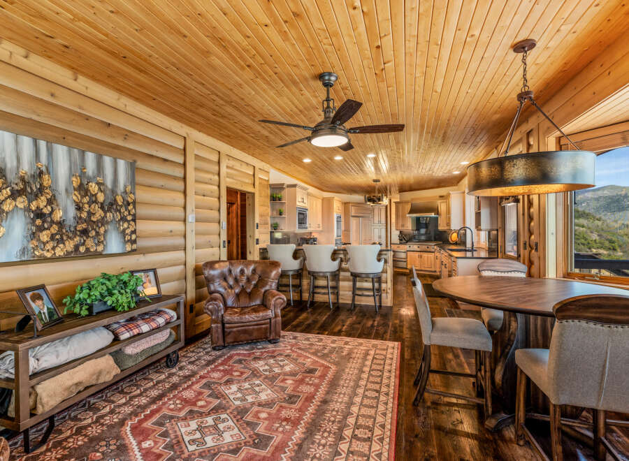 Experience rustic luxury in this stunning mountain home, featuring a spacious open-concept living area with a warm wood-paneled ceiling and walls.