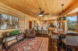 Experience rustic luxury in this stunning mountain home, featuring a spacious open-concept living area with a warm wood-paneled ceiling and walls.