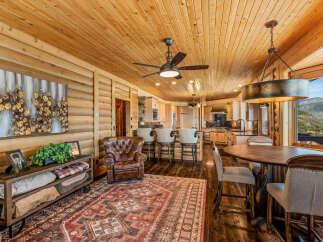 Experience rustic luxury in this stunning mountain home, featuring a spacious open-concept living area with a warm wood-paneled ceiling and walls.