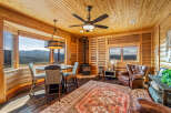 Experience cozy living in this charming log cabin featuring a rustic dining area with mountain views and a wood-burning stove for warmth.