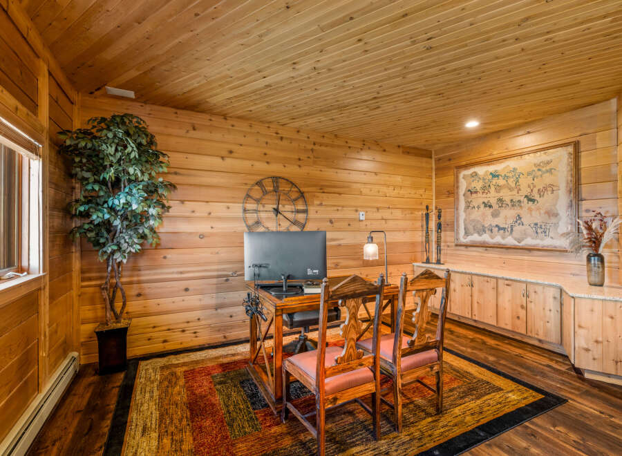 This rustic office space features warm wood paneling on the walls and ceiling, creating a cozy and inviting atmosphere.