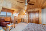 Experience rustic charm in this cozy bedroom featuring warm wood paneling throughout and a vaulted ceiling with a ceiling fan.