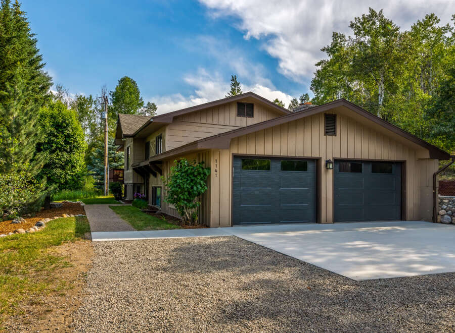 This charming home features a spacious two-car garage with modern dark gray doors, perfect for vehicle storage and hobbies.
