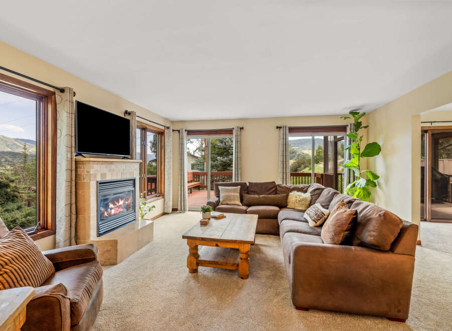 Cozy living room featuring a large sectional sofa, a stone-tiled fireplace with a roaring fire, and a rustic wooden coffee table.