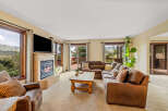 Cozy living room featuring a large sectional sofa, a stone-tiled fireplace with a roaring fire, and a rustic wooden coffee table.