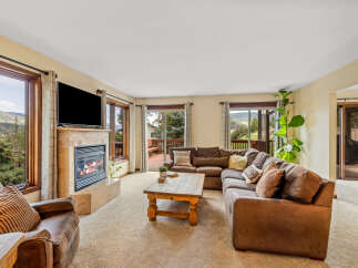 Cozy living room featuring a large sectional sofa, a stone-tiled fireplace with a roaring fire, and a rustic wooden coffee table.