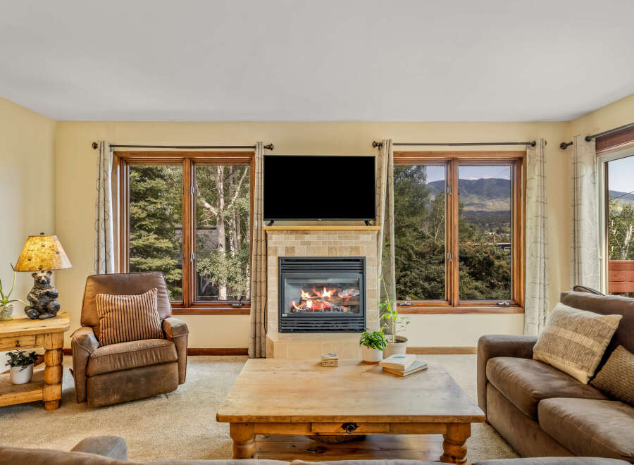 Cozy living room featuring a stone-tiled fireplace with a roaring fire, perfect for chilly evenings.