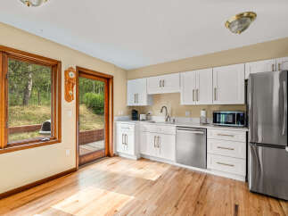 This kitchen boasts modern white cabinetry with elegant brass hardware, complemented by a sleek stainless steel dishwasher and refrigerator.