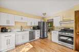 This kitchen boasts modern white cabinetry with elegant brass hardware, complemented by sleek quartz countertops.